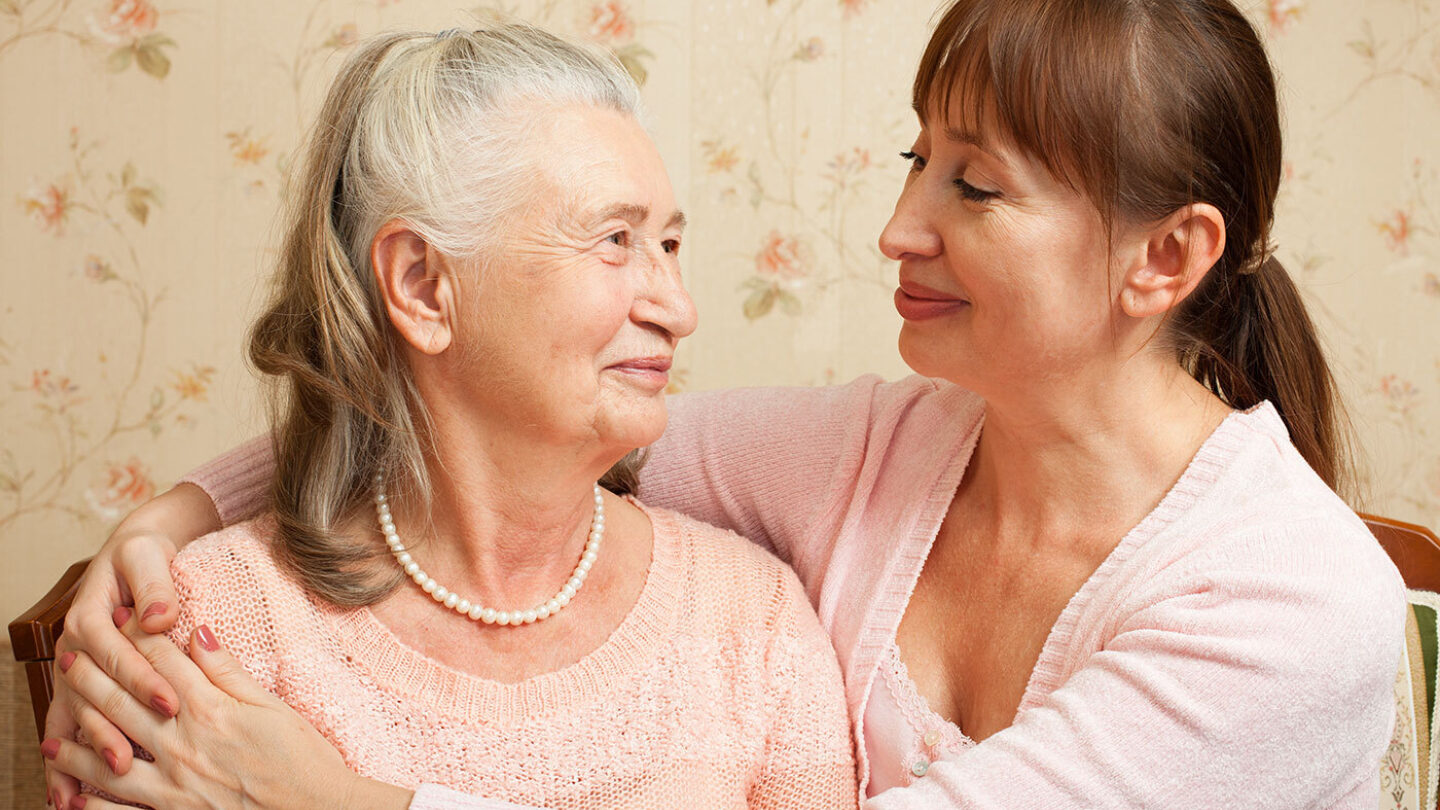 A carer embracing an older person. Both are smiling