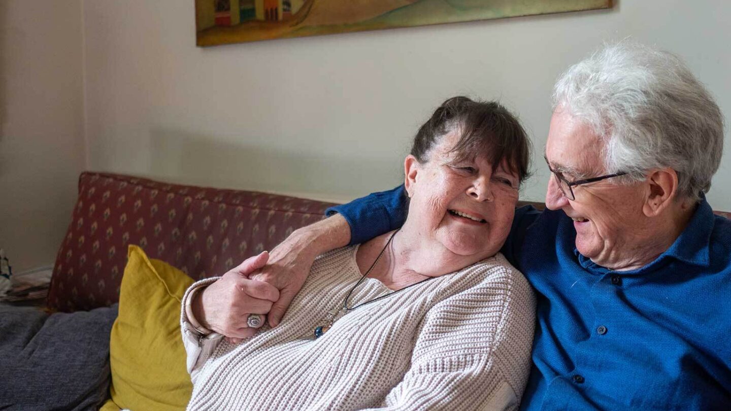 Two older people relaxing and laughing on a couch