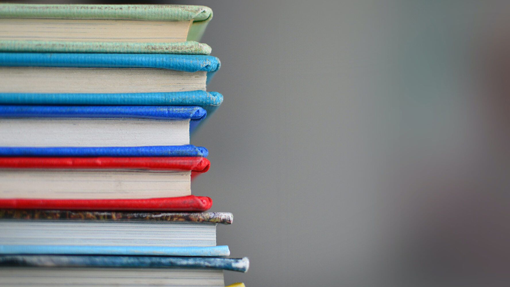 A stack of schoolbooks; the spines show a range of colours